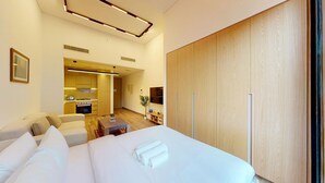 Una habitación de hotel moderna con una cama grande, un sofá, una mesita pequeña y un armario de madera.