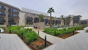 Un edificio moderno con varios pisos, espacios para sentarse al aire libre y jardines ajardinados.