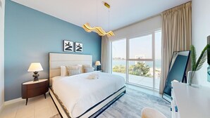 Una habitació d'hotel moderna amb un llit gran, una taula de treball i vista al mar.