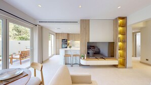 Un salon moderne doté d’un grand téléviseur, d’un canapé et d’un coin repas avec une table et des chaises.