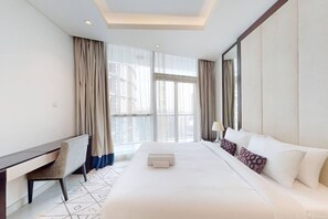A hotel room with a large bed, a desk, and a chair. There is a window with curtains and a view of buildings outside. - Premium 2 Bed -Iconic Burj Khalifa View I Downtown (Downtown Dubai)