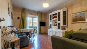 Ein Wohnzimmer mit Esstisch, Sofa, Fernseher und Dekorationselementen.