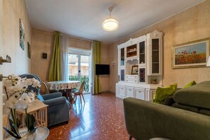 Ein Wohnzimmer mit Esstisch, Sofa, Fernseher und Dekorationselementen.