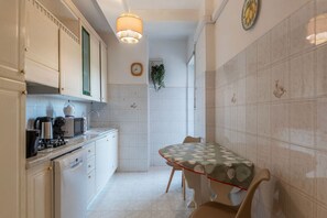 A kitchen with white cabinets, a microwave, a coffee maker, and a dining table with chairs. - GuestHost - Comfortable 80 sqm apartment, perfect for 4 people, located on the sixth floor of a building with a lift.The property is located a few steps from Trastevere Station, in a well-served area and excellently connected to the center of Rome. The s (Rome)