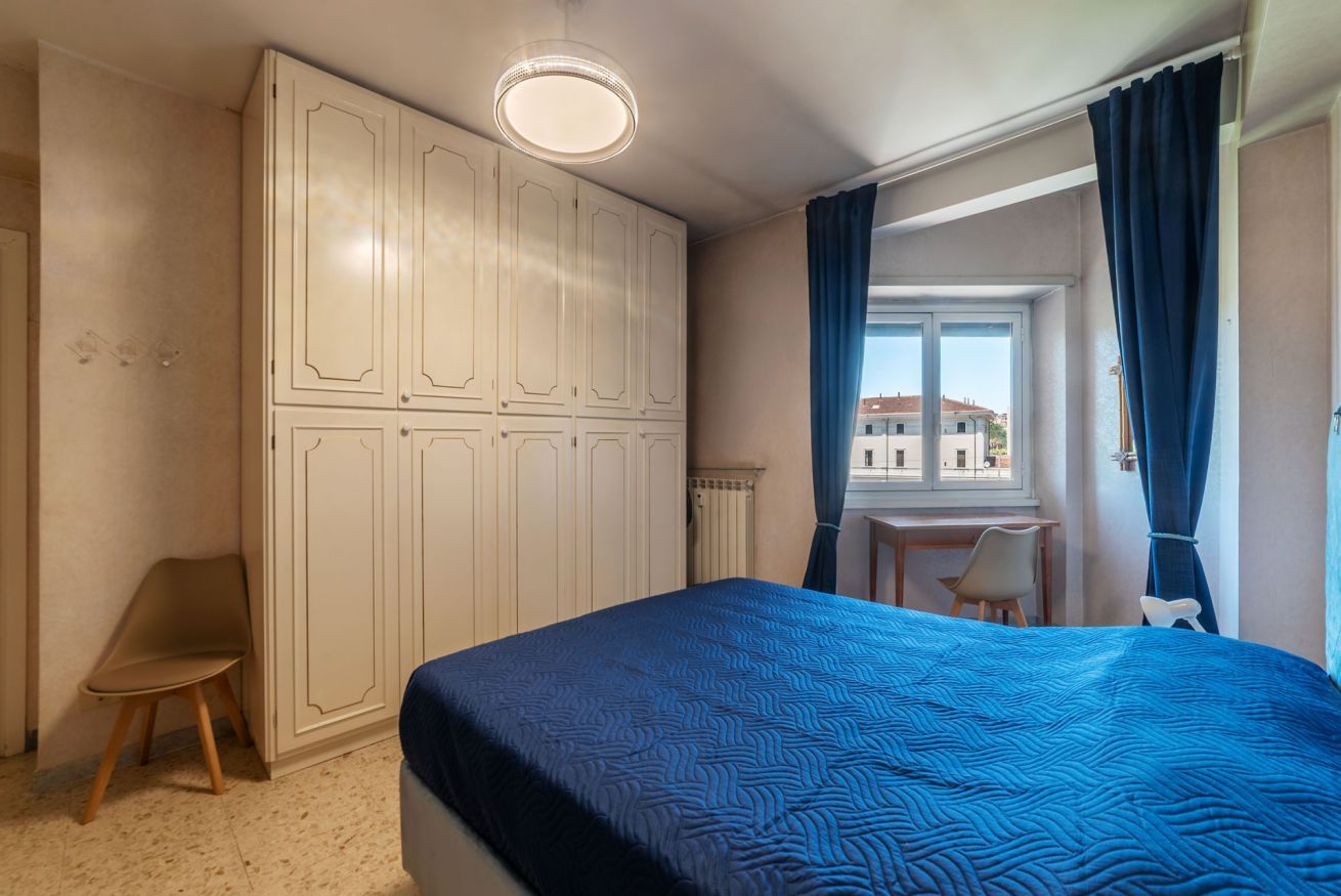 A bedroom with a bed, a desk, a chair, and a wardrobe.