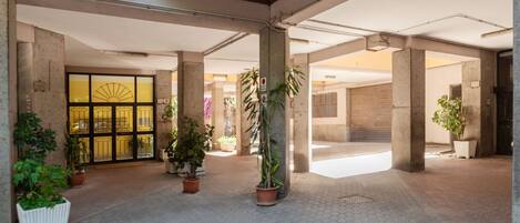 Un vaste espace intérieur doté de piliers en béton, de plantes en pot et d’un sol carrelé.