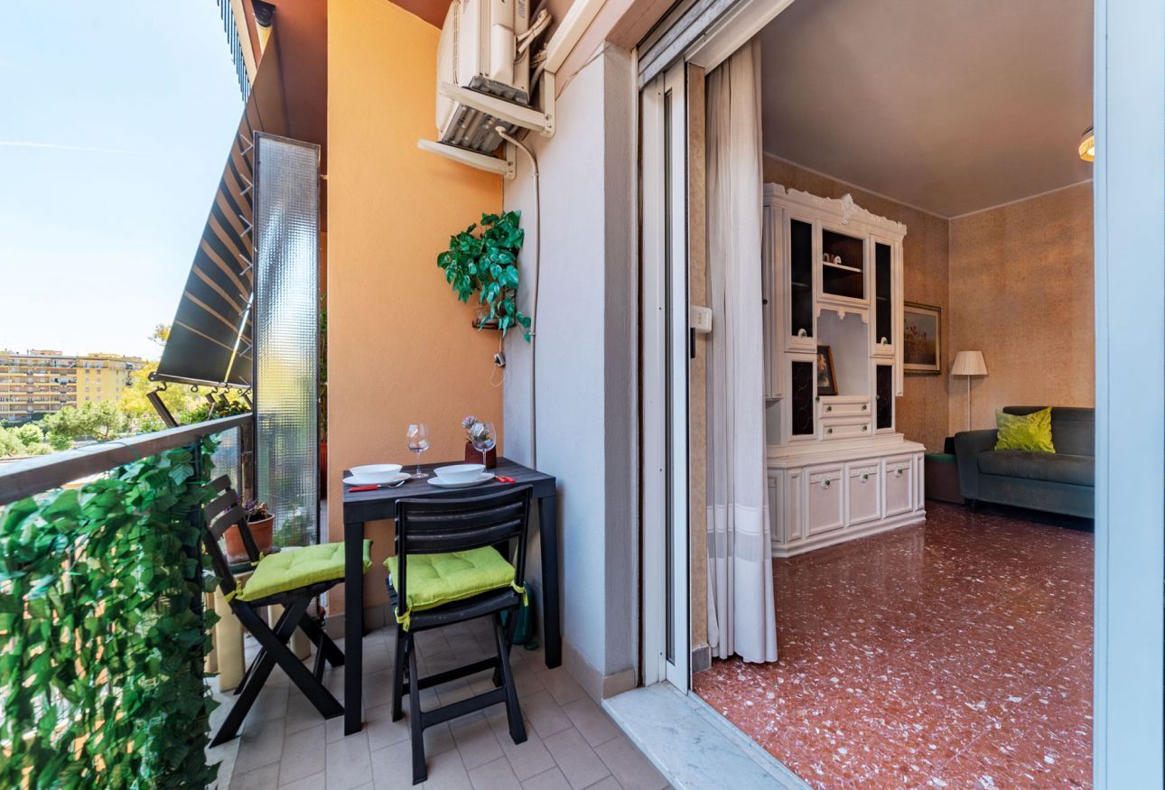 Un balcon avec une table, des chaises et un pot de fleurs.