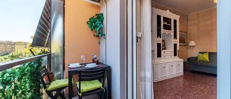 A balcony with a table, chairs, and a potted plant.