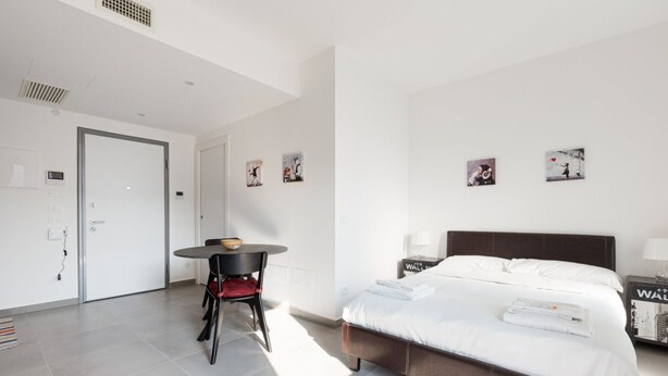 Quarto de hotel moderno com uma cama, uma mesinha redonda e obras de arte nas paredes.