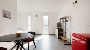 Quarto moderno com mesa de jantar, geladeira vermelha e armário com prateleiras.