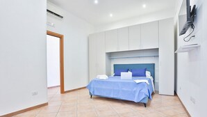 Ein Schlafzimmer mit einem Bett, einem Schreibtisch und einem an der Wand montierten Fernseher.