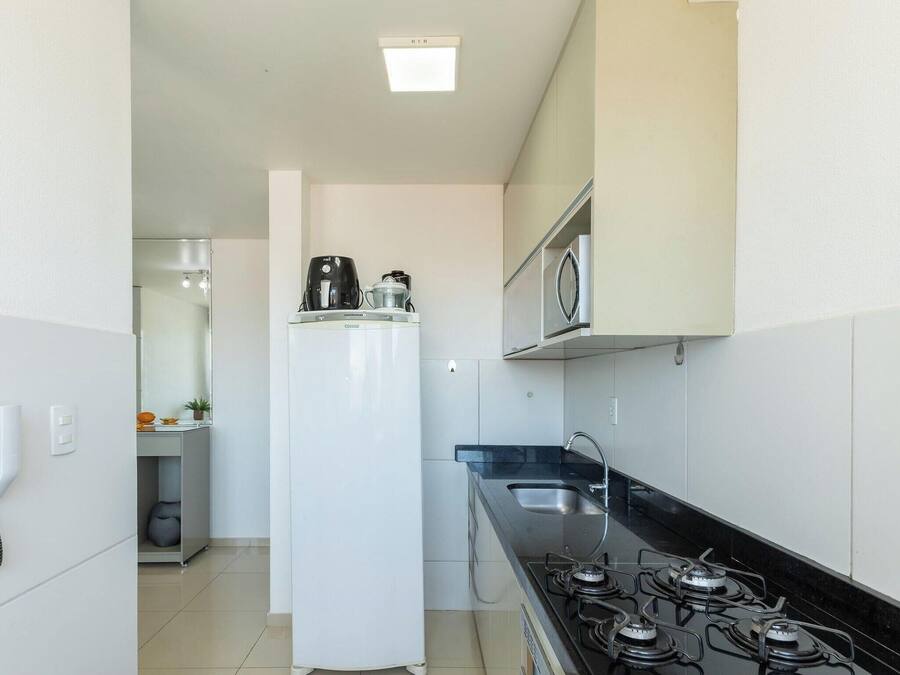 Cocina compacta con refrigerador, estufa, microondas y una pequeña superficie de encimera.