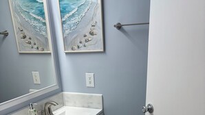 A bathroom with a white sink, a mirror, and two framed pictures of the ocean. - 2BR 1B condo Amelia island, 2 blocks beach 2 miles downtown 1 mile Fort Clinch (Fernandina Beach)