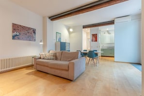 Ein Wohnzimmer mit einer Couch, einem Esstisch mit Stühlen, einer Küchenzeile und einem Heizkörper.