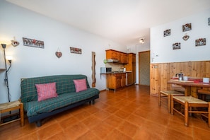 Un espacio de sala de estar acogedor con un sofá, una mesa de comedor y una cocina al fondo.