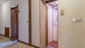 A hallway with wooden doors, a carpeted entrance, and a light switch on the wall. - GuestHost - In Tarvisio, a cozy 35 sqm studio for 2 guests, located on the second floor of a residential building with an elevator (not suitable for disabled persons). Surrounded by greenery, the building offers an open view of the city center, the sport (Tarvisio)