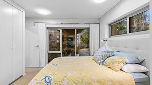 A bedroom with a bed, a window, and a sliding glass door leading to a balcony. - The Villa at Maloneys (Maloneys Beach)