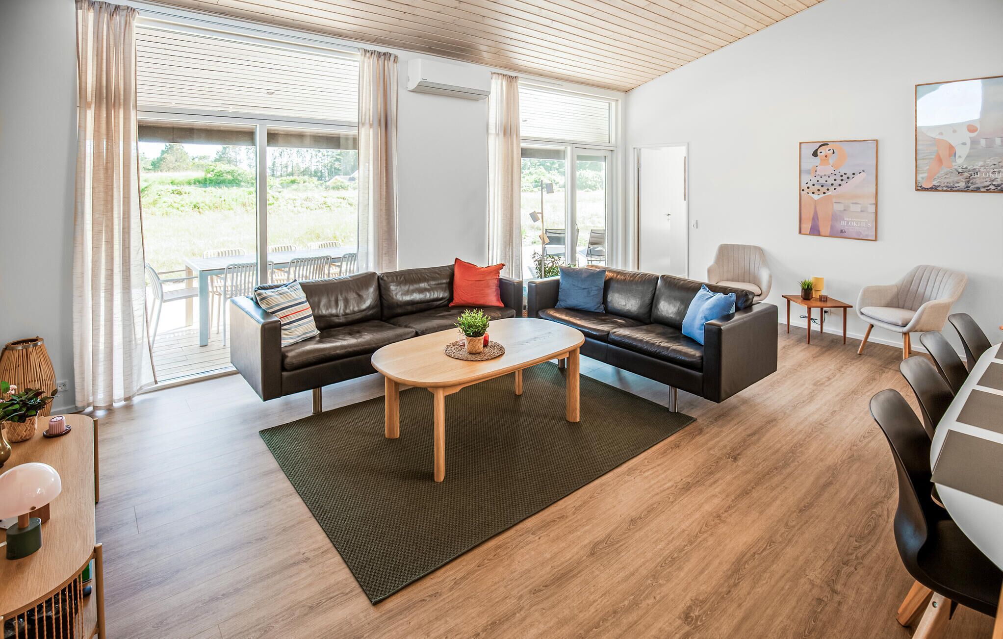 Uma sala de estar moderna com um sofá seccional, uma mesa de centro e vista para o exterior através de grandes janelas.