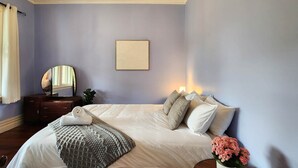 Una camera da letto con un letto grande, un comodino, uno specchio, un quadro appeso al muro e un lampadario.