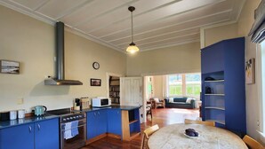Un'ampia cucina con mobili blu, un tavolo da pranzo in legno e vista su un soggiorno.