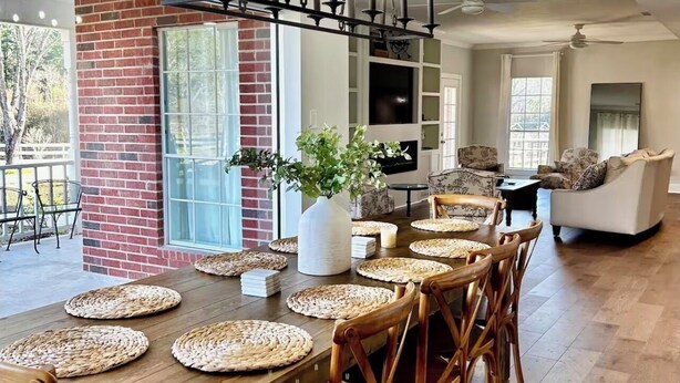 A dining area with a long wooden table, woven placemats, and wooden chairs. - Beautiful Private 30 Acre Nature Retreat/Pool
Ideal for family/groups sleeps 16 (Plantersville)
