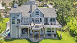 A large, two-story house with a wrap-around porch, multiple windows, and a garage. - Luxury Lakefront Retreat (Graford)