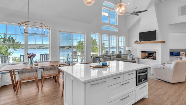 A spacious kitchen with a large island, white cabinetry, and a view of the ocean. - Luxury Lakefront Retreat (Graford)