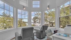 A bright room with large windows, a desk, and two chairs. - Luxury Lakefront Retreat (Graford)