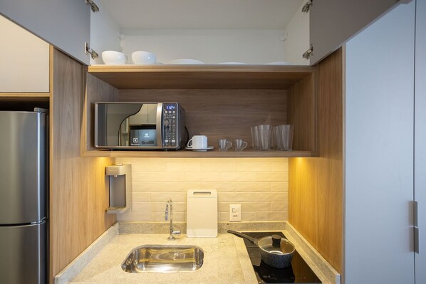 A compact kitchen with a microwave, sink, and a small countertop area. - For You Perdizes (São Paulo)