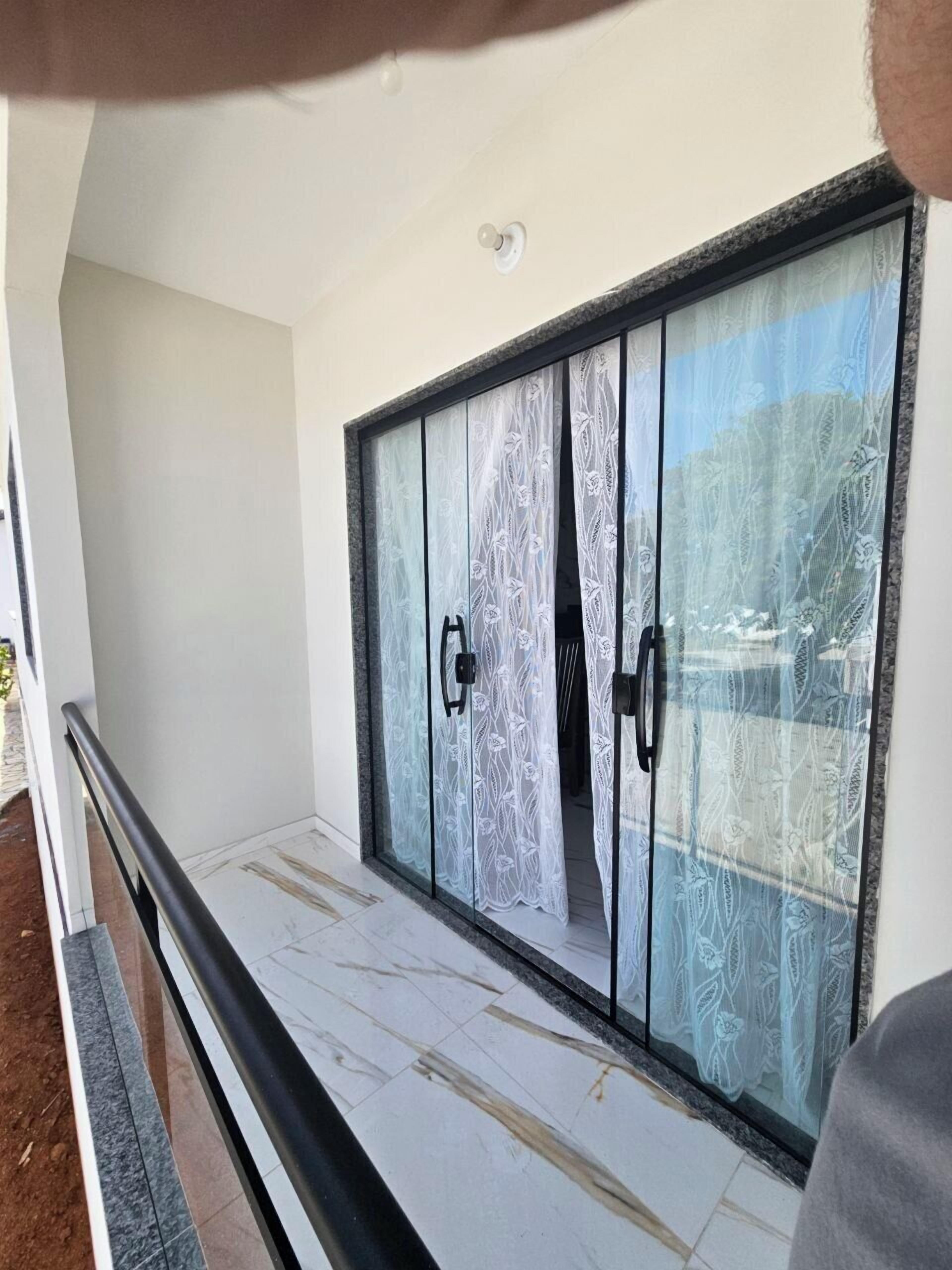 A room with a large sliding glass door with a floral pattern, a black metal railing, and a tiled floor.
