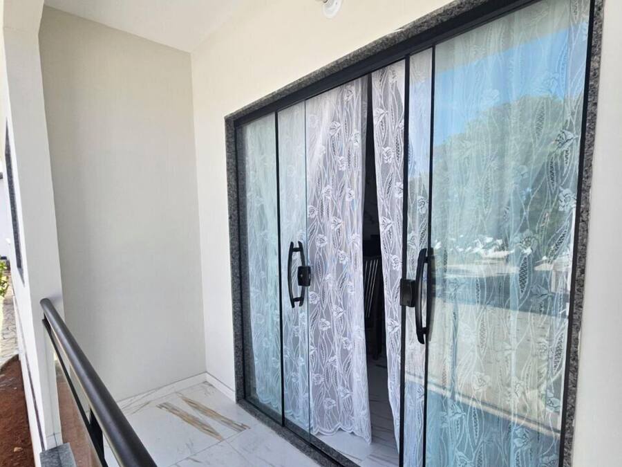 A room with a large sliding glass door with a floral pattern, a black metal railing, and a tiled floor.