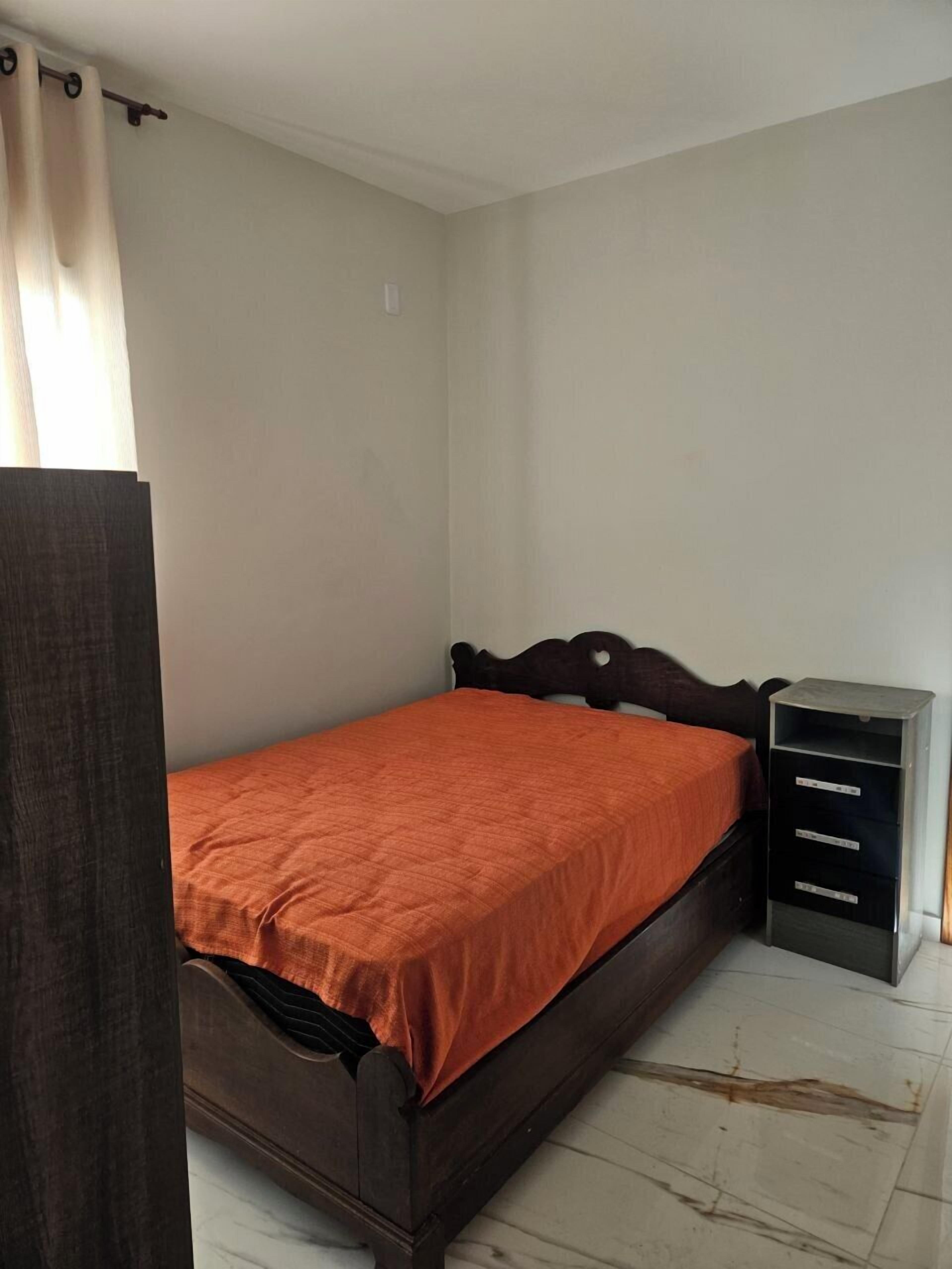 Une chambre à coucher avec un lit en bois, une table de chevet et une armoire.