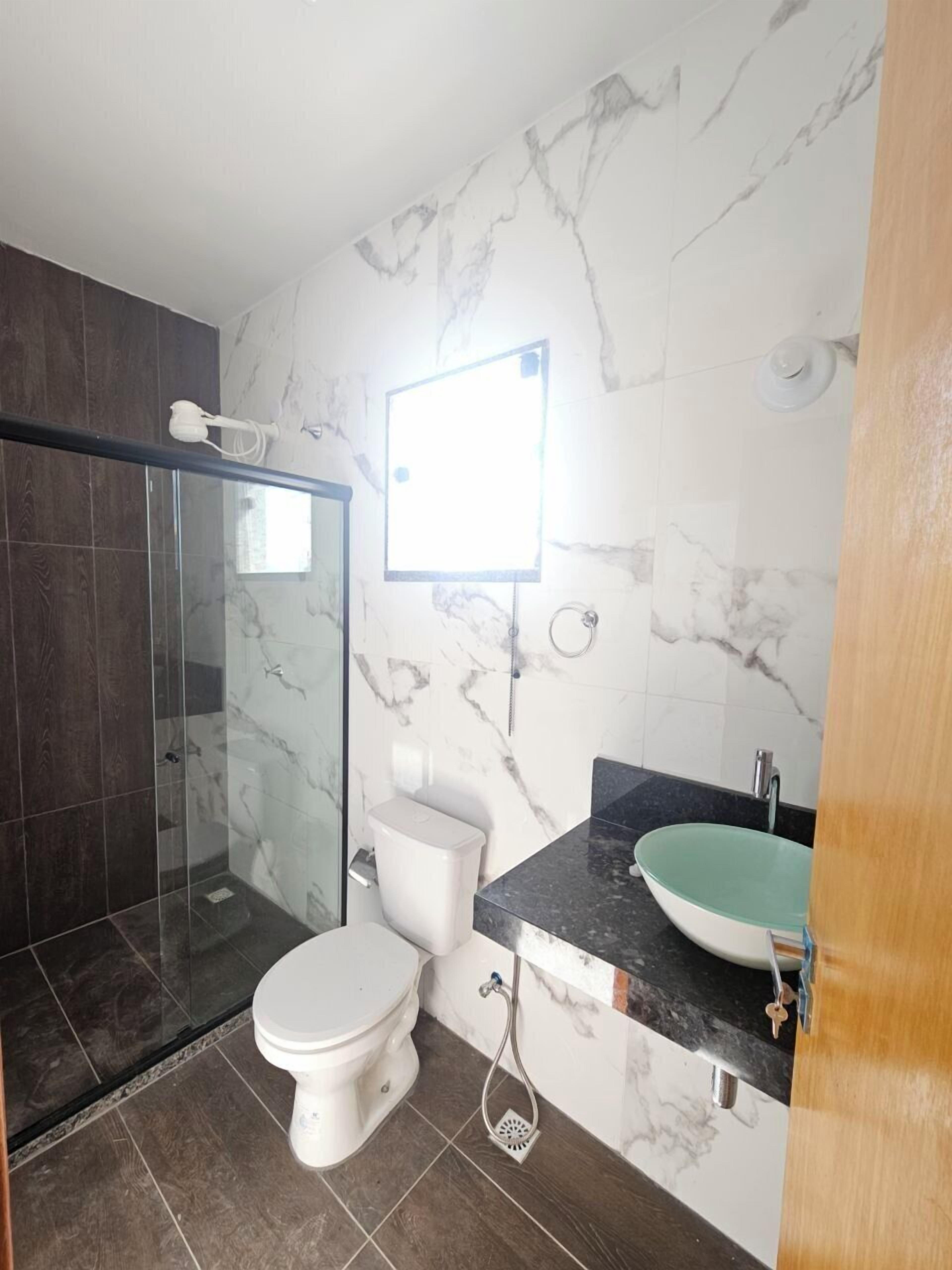 Ein modernes Badezimmer mit Duschabtrennung aus Glas, Toilette und Waschbecken mit Marmorablage.