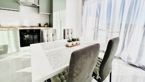 Una cocina moderna con comedor, que incluye una mesa con sillas y una ventana con cortinas.