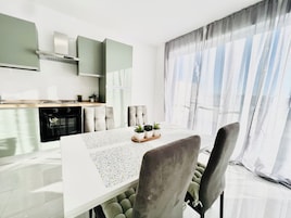 Una cucina moderna con zona pranzo, comprensiva di tavolo e sedie, e una finestra con tende.