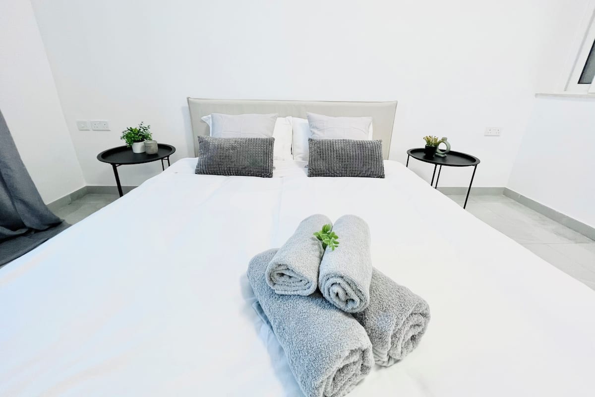 A hotel room with a large bed, two bedside tables, and a window.