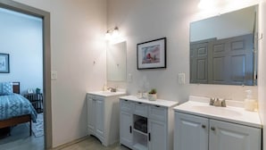 A modern bathroom with two sinks, a large mirror, and a framed picture on the wall. - Tucson Summer Base | 4BR Modern Duplex Retreat (Tucson)