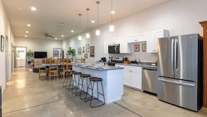 A spacious kitchen with white cabinets, stainless steel appliances, and a central island with bar stools. - Tucson Summer Base | 4BR Modern Duplex Retreat (Tucson)