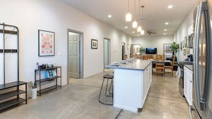 A modern kitchen with a central island, stainless steel appliances, and a dining area with wooden chairs. - Tucson Summer Base | 4BR Modern Duplex Retreat (Tucson)