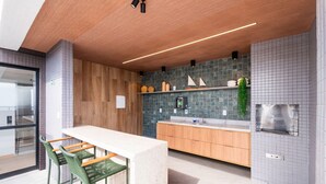 Una cocina moderna con techo de madera, encimera blanca y una silla verde.
