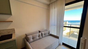 Un salón moderno con un sofá, un ventanal con vista al océano y un radiador.