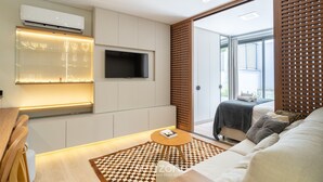 A modern living room with a flat-screen TV, a glass cabinet with decorative items, a cozy sofa, and a patterned rug. - Studio 300m From Beira-mar Norte Msg0101 (Florianópolis)