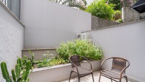A patio area with two wicker chairs, a potted plant, and a wall-mounted air conditioning unit. - Studio 300m From Beira-mar Norte Msg0101 (Florianópolis)