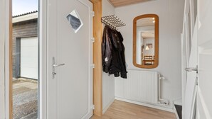 A room with a white door, a wooden ceiling, a radiator, and a coat rack with jackets. - Nice home in Thyborøn with WiFi (Thyborøn)