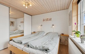 A bedroom with a large bed, a mirror, a clock, and a window with a plant. - Nice home in Thyborøn with WiFi (Thyborøn)