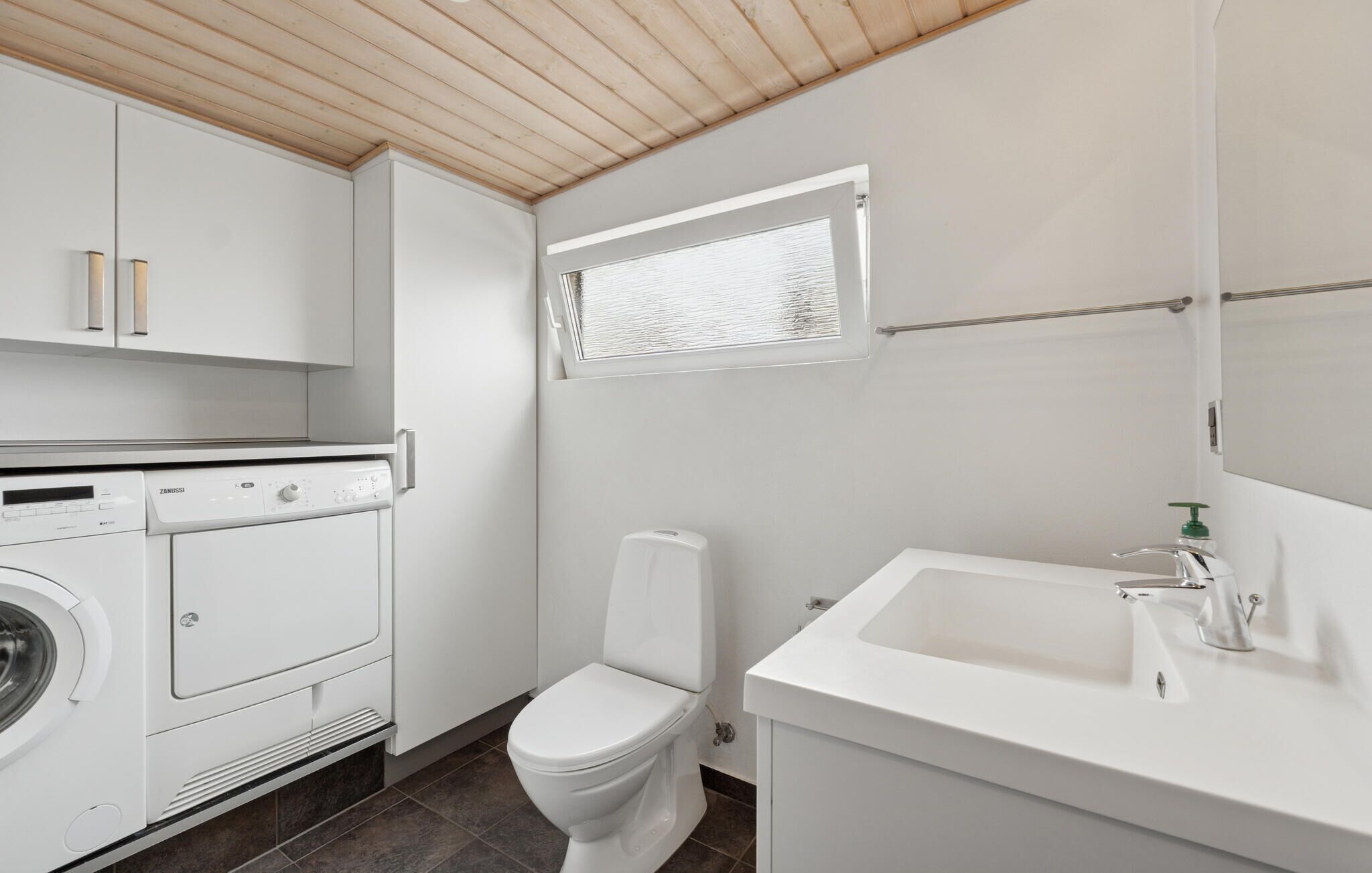 Ein kleines, modernes Badezimmer mit Waschmaschine, Toilette und Waschbecken.