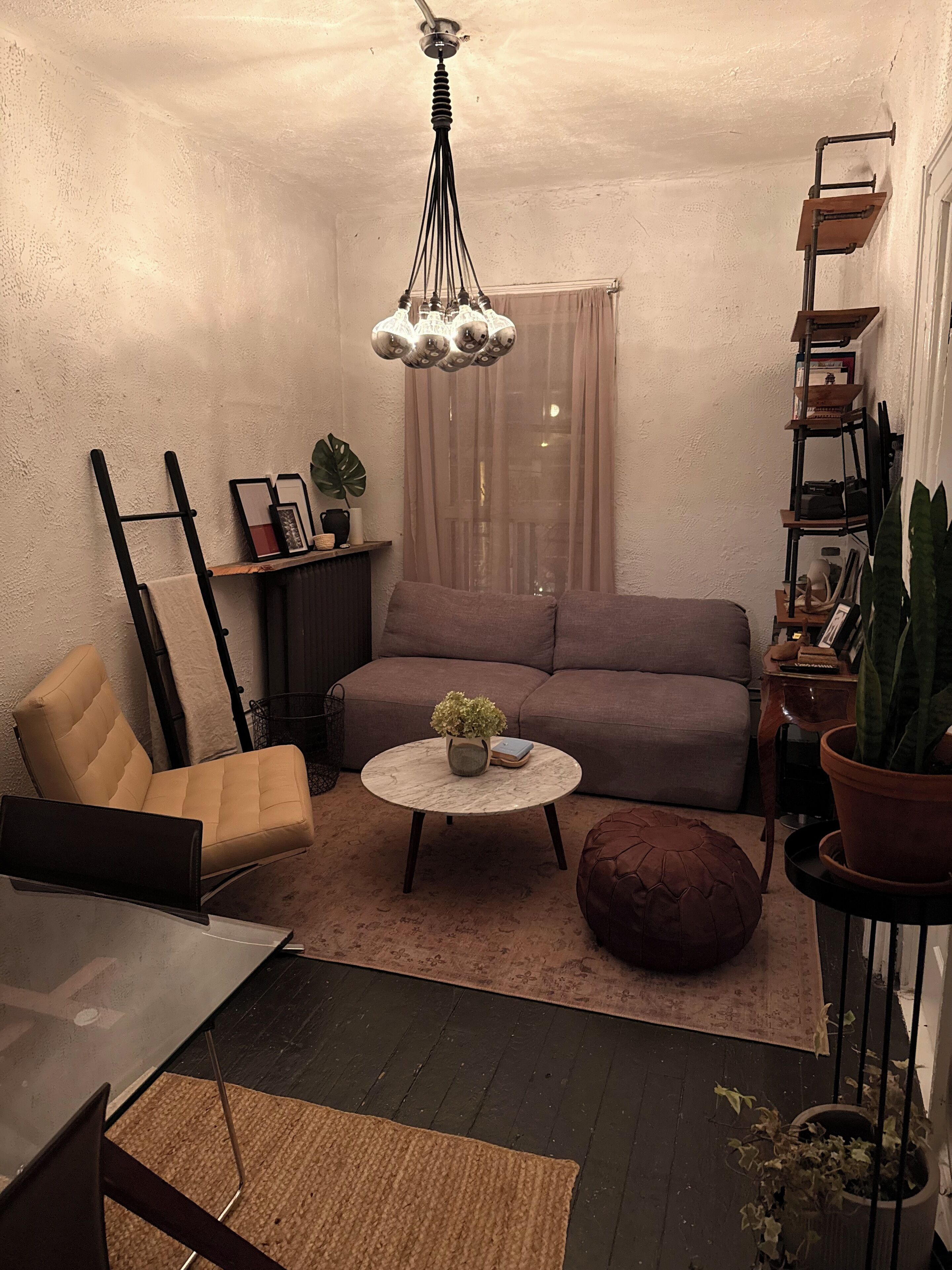 Ein gemütliches Wohnzimmer mit einer Couch, einem Sessel, einem Couchtisch und einem Bücherregal.
