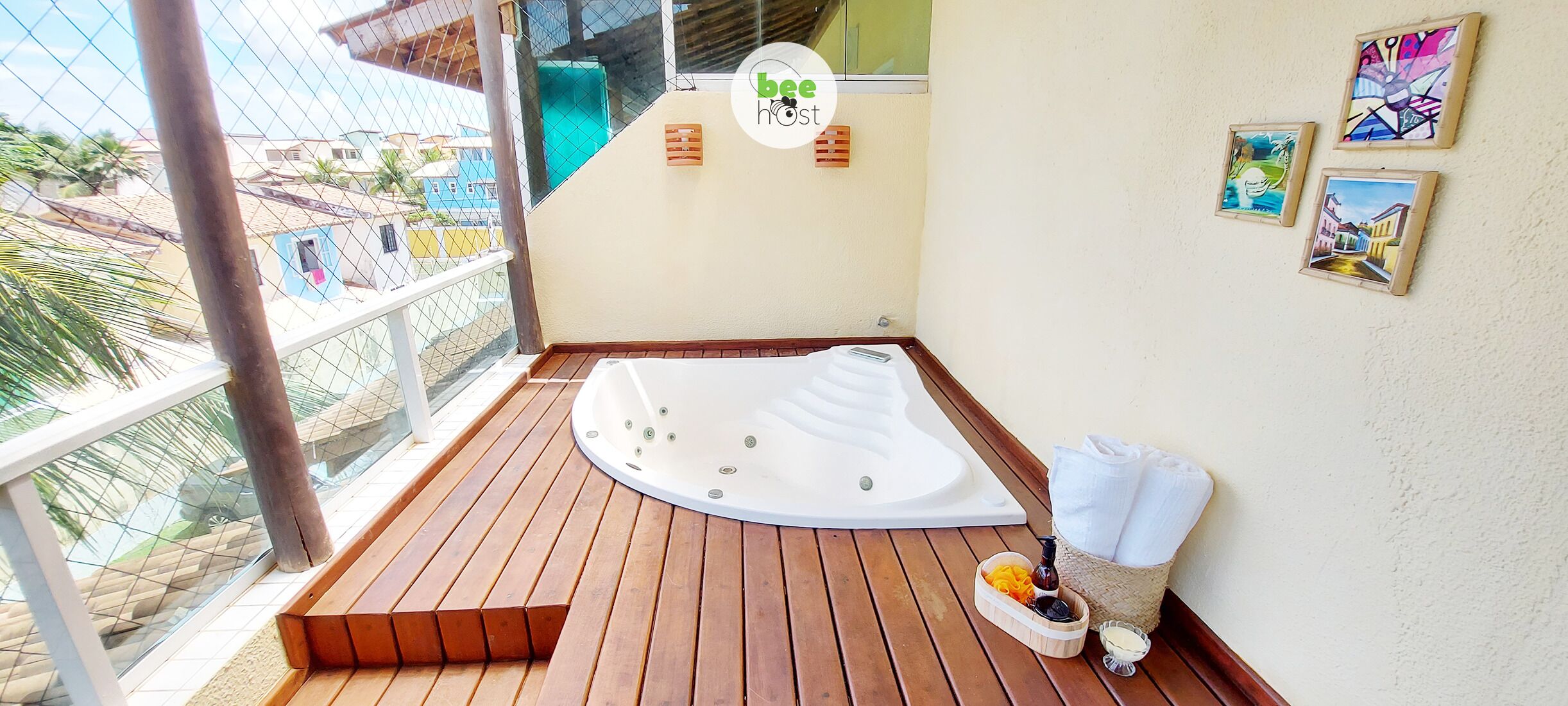 Un balcón con piso de madera, un jacuzzi y un pequeño rincón de estar. Hay tres cuadros enmarcados en la pared.