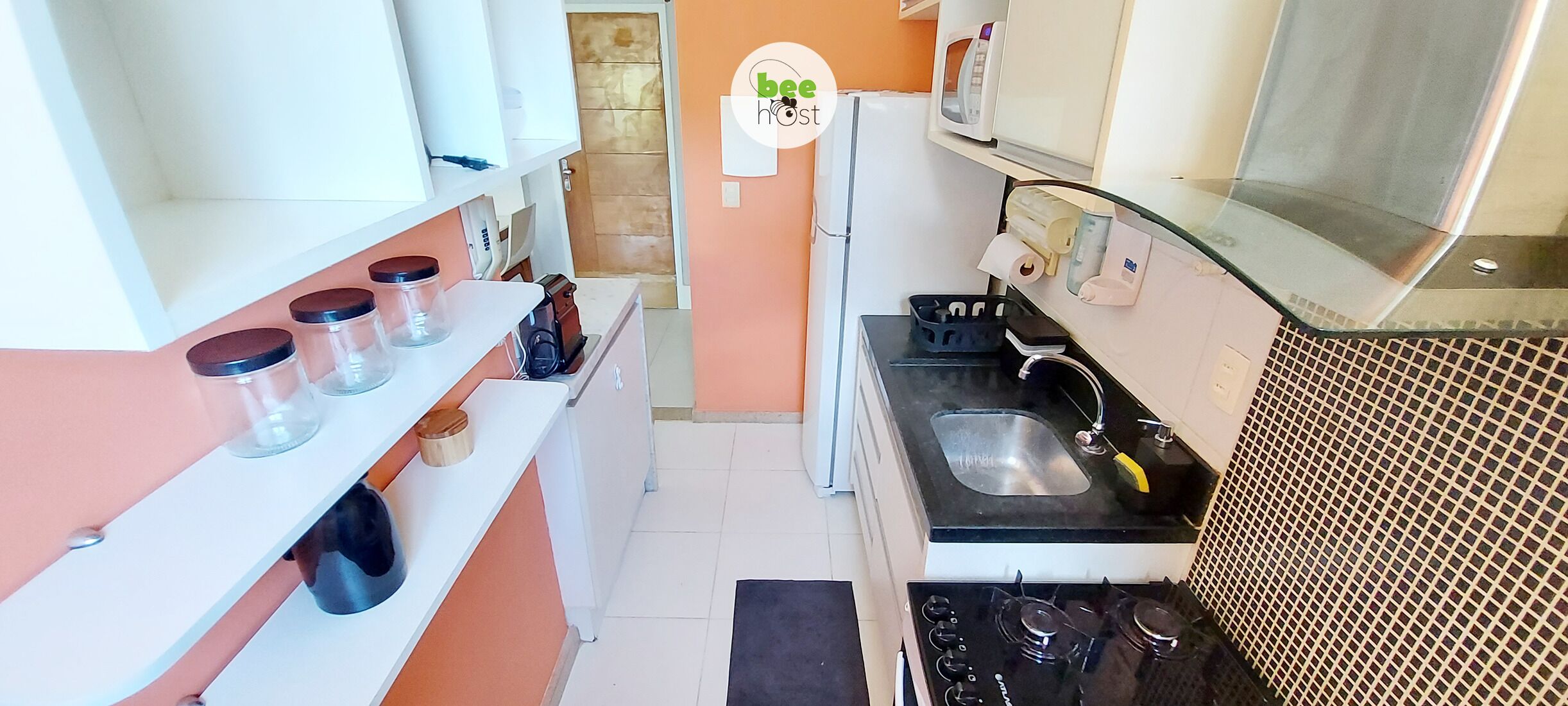 A compact kitchen with a gas stove, sink, and countertop storage.