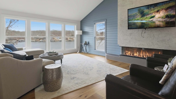 Una sala de estar moderna con chimenea, ventanas amplias y un televisor de pantalla plana.